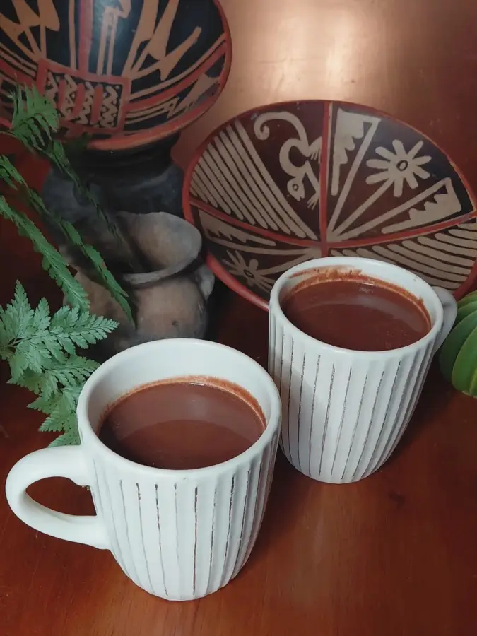 Two cups of warm cacao beside hand-painted Ecuadorian ceramics
