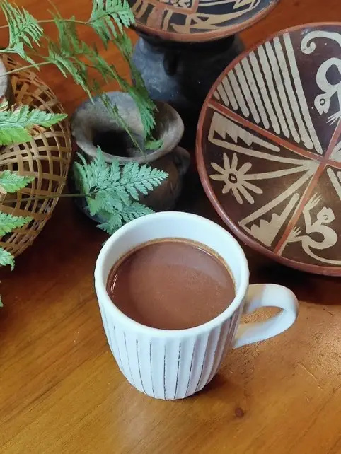 A cup of cacao on a painted ceramic plate