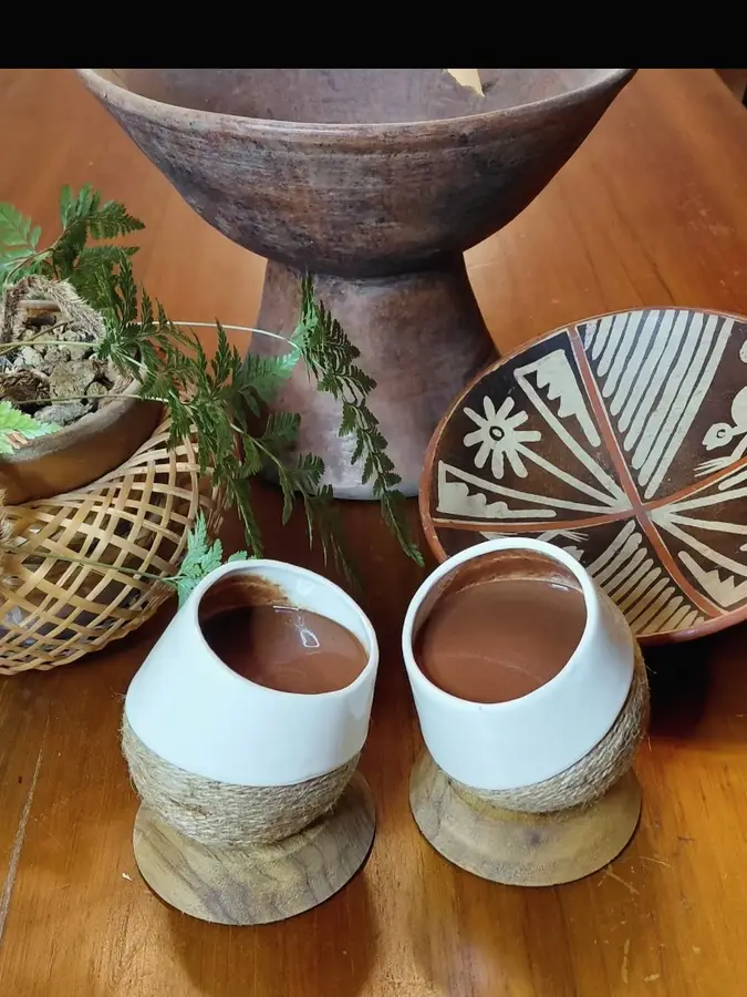 Cacao poured into cups beside a carved bowl